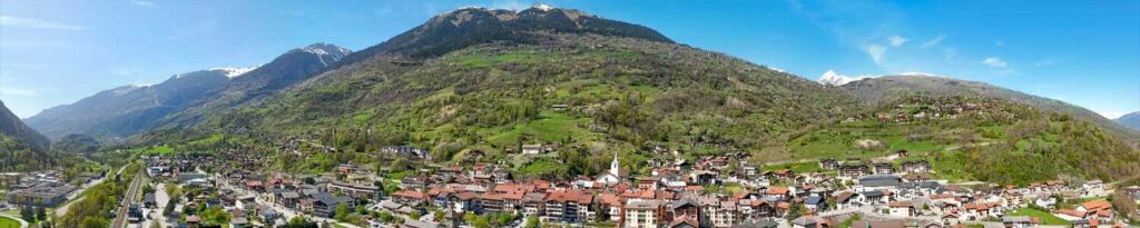 Vue aérienne panoramique d'Aime avec effet fish-eye, avec l'église au centre et des montagnes du Beaufortain en arrière plan