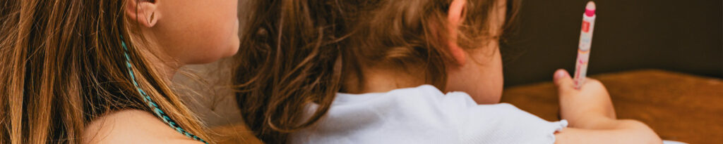 Panoramique de deux enfants de dos dont l'une tient un crayon