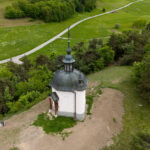 Vue en plongée de la chapelle de Longefoy entourés d'arbres et de champs verts