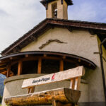 Chapelle de Tessens avec un banc en bois, incrusté du logo d'Aime-la-Plagne, au premier plan