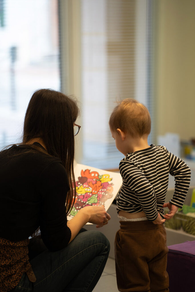 Animatrice avec des lunettes montrant un livre avec un dessin à un enfant
