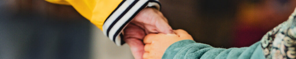 Un adulte et un enfant se tenant la main avec plusieurs personnes flou en arrière plan