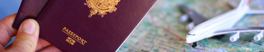 Main tenant un passeport à côté d'une figurine d'avion posé sur une carte routière