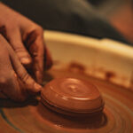 Les mains façonnent un bol d'argile sur un tour de poterie.