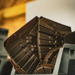 Semelle de chaussures en plastique, empilées dans un récipient en plastique gris.