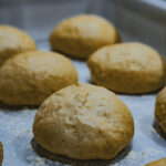 Les petits pains ronds sont placés sur une plaque de cuisson farinée, prêts à être cuits.