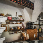 Intérieur d'un magasin de glaces accueillant avec un menu sur tableau, des pots de garnitures, une machine à café et des coupes sur des étagères.