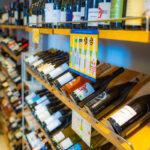 Bouteilles de vin présentées sur des étagères en bois dans un magasin de vin, classées par type.