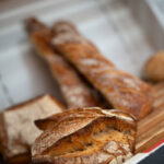 Pains et baguettes artisanales croustillants présentées sur l'étagère d'une boulangerie.