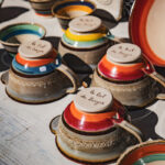 Bols en céramique colorés présentés sur une table en bois lors d'un marché en plein air.