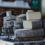 Des meules et des quartiers de tomme sont exposés sur un étal de marché.