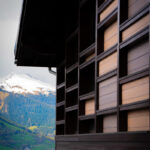 Bâtiment moderne en bois avec un paysage de montagne et un pic enneigé visible en arrière-plan.