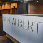 Bureau de réception moderne avec MONTALBERT gravé sur la face avant, dans un intérieur de bâtiment élégant.