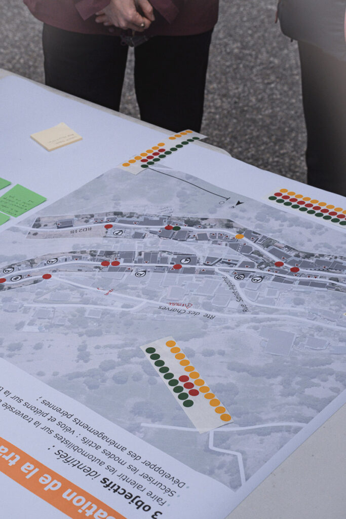 Vue d'un plan imprimé d'une rue de la commune annoté avec des gommettes vertes, jaunes et rouges ; sur une table devant des personnes