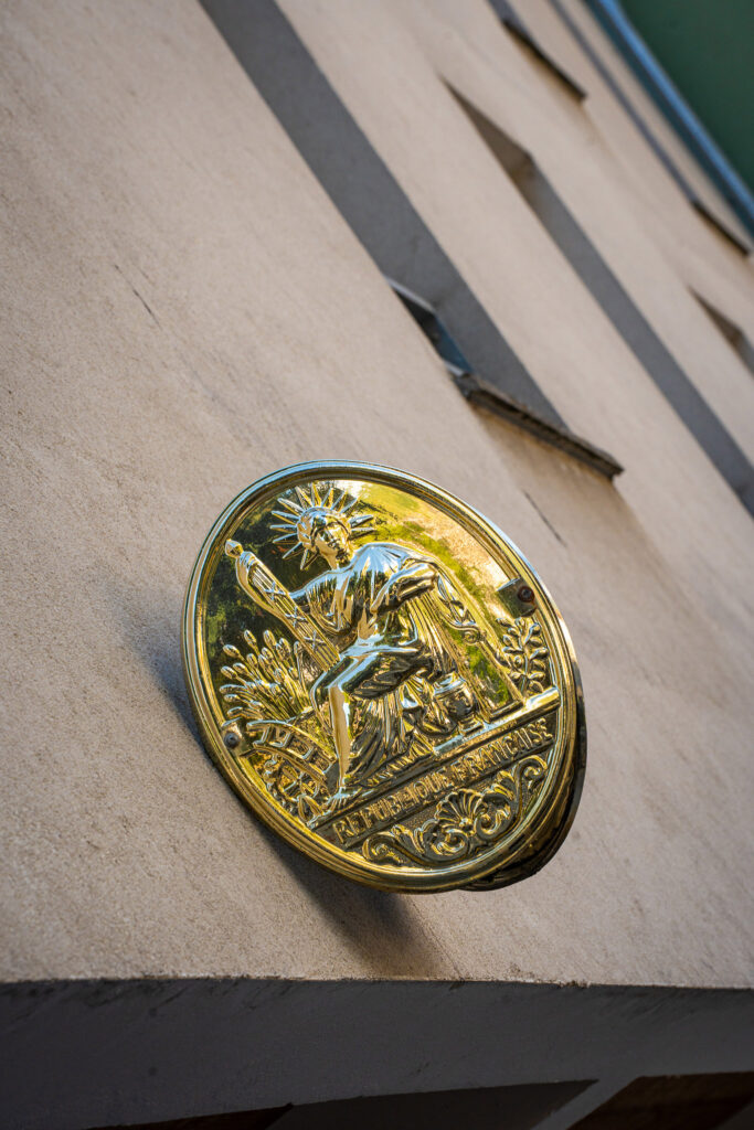 Blason doré des notaires sur la façade grise d'un bâtiment