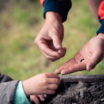 Employé aux espaces verts de la commune montrant un insecte à un enfant