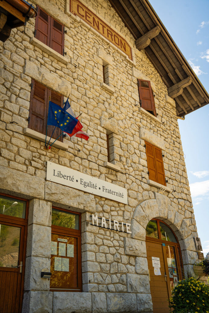 Façade du bâtiment de la gare de Centron avec l'enseigne écrit Mairie, la devise française "Liberté, Égalité, Fraternité" et les drapeaux de l'Europe, de la France et de la Savoie