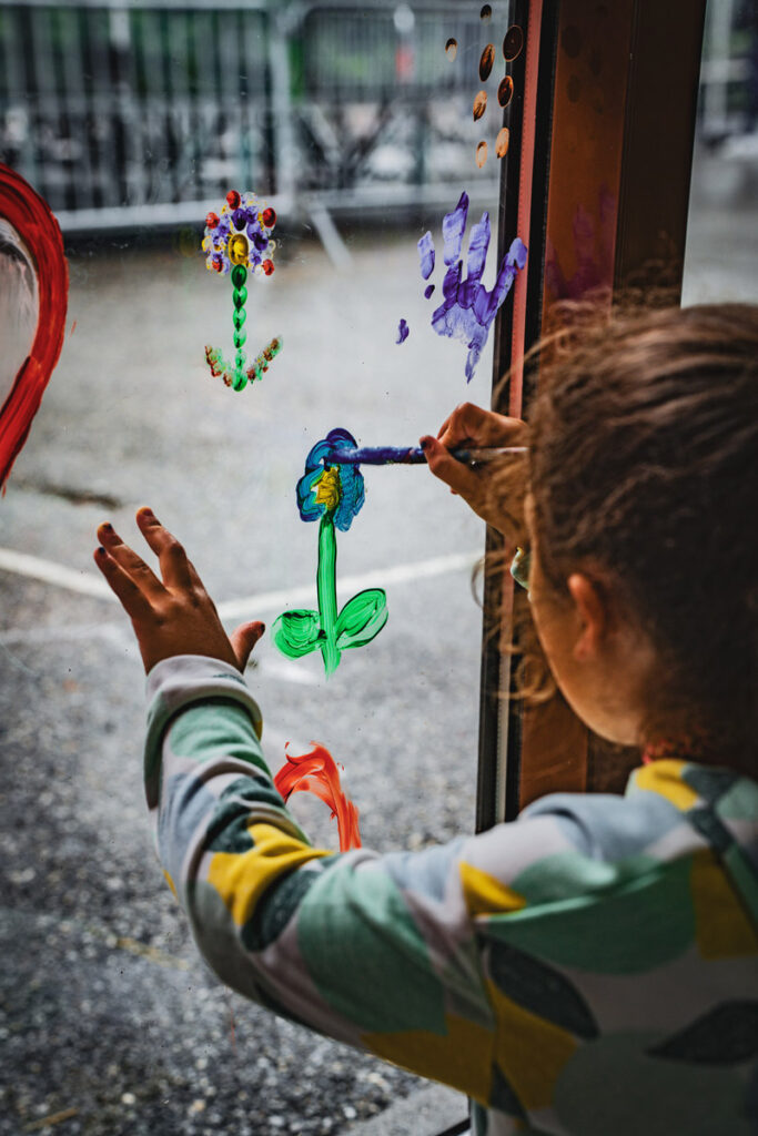 Enfant peignant une fleur sur une fenêtre