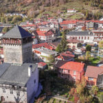 Vue aérienne de la tour Montmayeur et du centre ville d'Aime entourée d'arbres d'automne.
