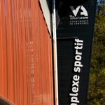 Façade orange et noire portant l'enseigne et le logo du complexe sportif de la Communauté de Communes es Versants d'Aime