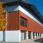 Façade orange et noire portant l'enseigne et le logo du complexe sportif de la Communauté de Communes es Versants d'Aime