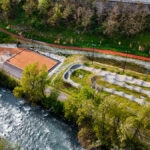 Vue aérienne d'une pumptrack et de terrains de pétanque bordés à leur gauche par la piste cyclable et la rivière Isère
