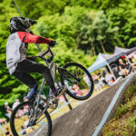 Jeune garçon sur son vélo, casqué et en habit de cycliste, sur les bosses de la pumptrack