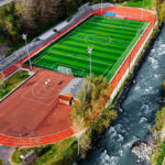 Vue aérienne du stade de football Albert Perrot entouré d'une piste d'athlétisme et de terrains de basket et bordé à sa droite par la rivière Isère et la piste cyclable